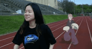 a girl walking on a football stadium with a virtual character behind her